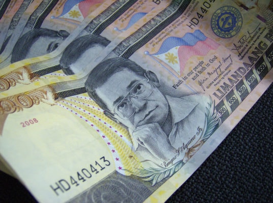 A stack of Philippine Pesos fanned across a table.