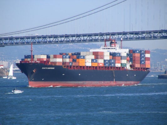 A shipping vessel passing under a bridge.