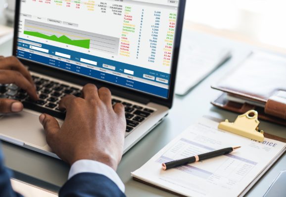 A man typing numbers into a financial report on a laptop.