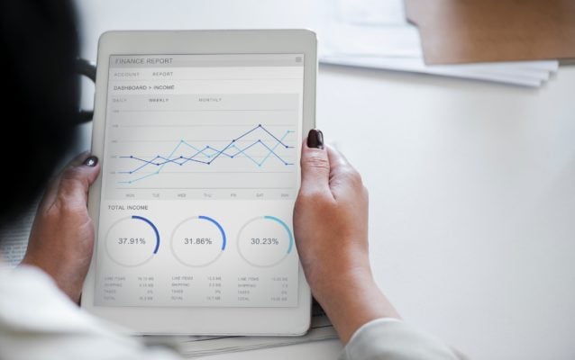A lady holding a tablet with a financial report on the screen.