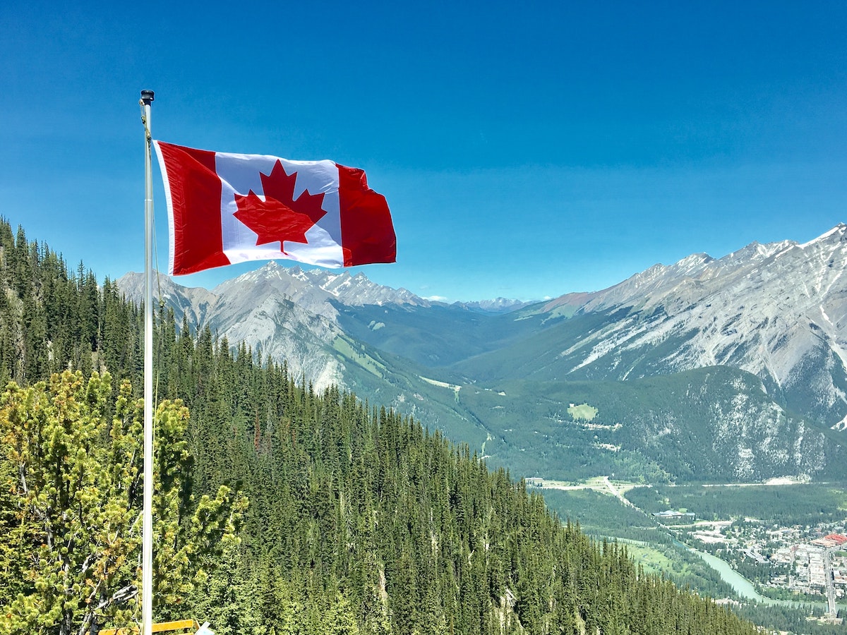 The Canadian flag flying above mountains in Canada.