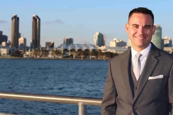 An insurance broker smiling in the foreground of a city.