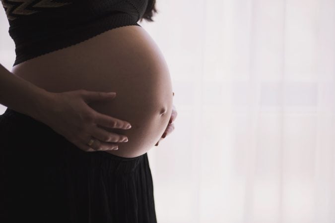 A pregnant woman holding her belly.
