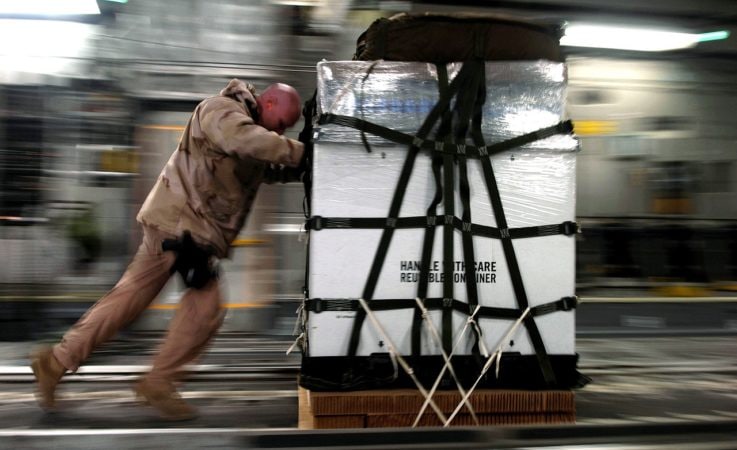 A man pushing a pallet of cargo.