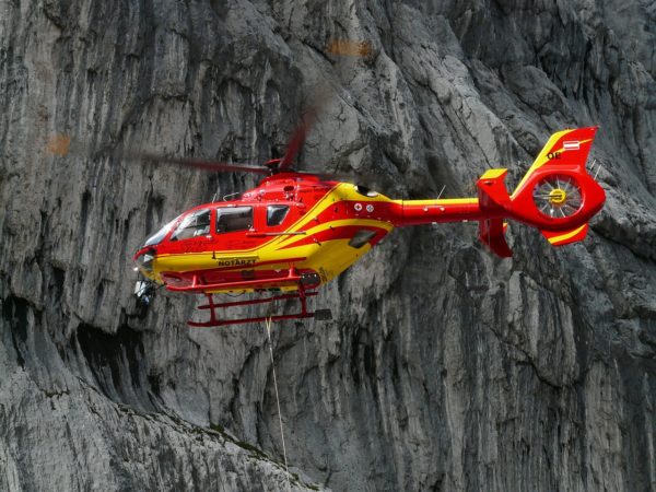 A medical helicopter in the foregroud of some mountains.