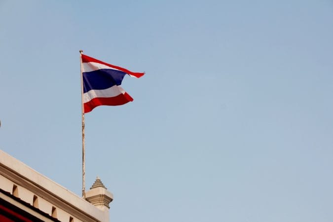 A Thai flag flying above a building.