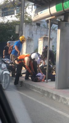 A motorcycle taxi driver tending to a student he hit with his motorbike..