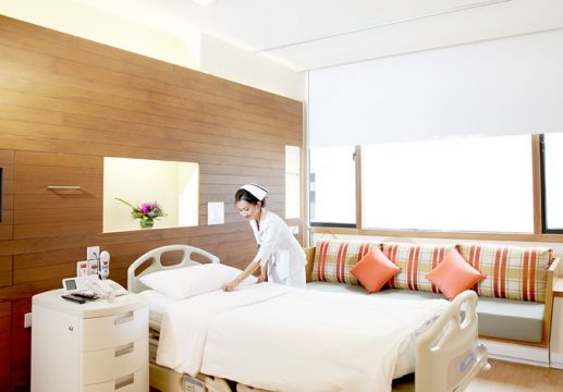 A nurse making a bed in a hospital room.