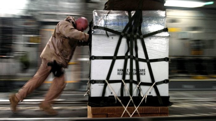 A man pushing a pallet of cargo.