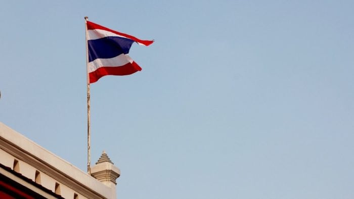 A Thai flag flying above a building.