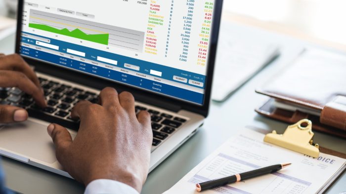 A man typing numbers into a financial report on a laptop.