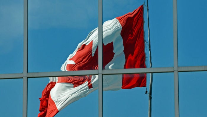 The reflection of the Canadian flag in the windows of an office building.
