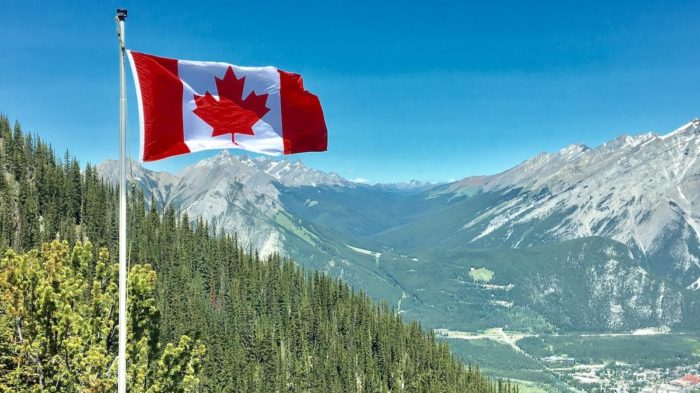 The Canadian flag flying above mountains in Canada.
