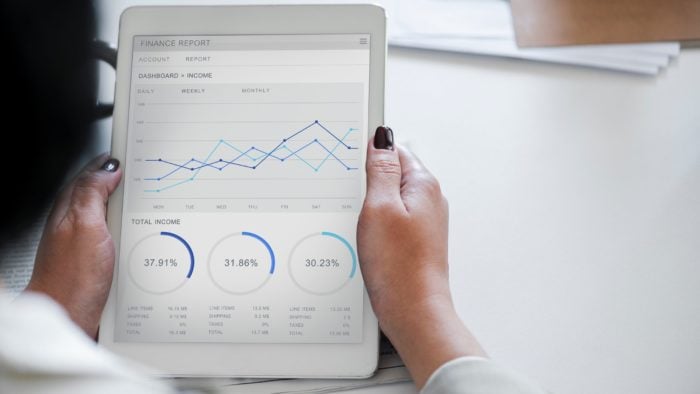 A lady holding a tablet with a financial report on the screen.