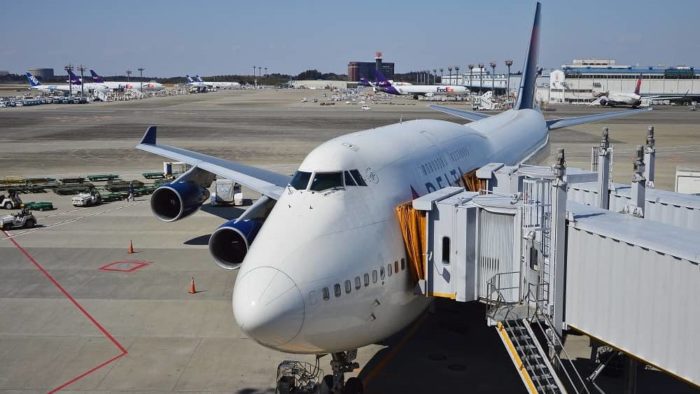 An airplane parked next to an airport terminal, connected by a corridor.