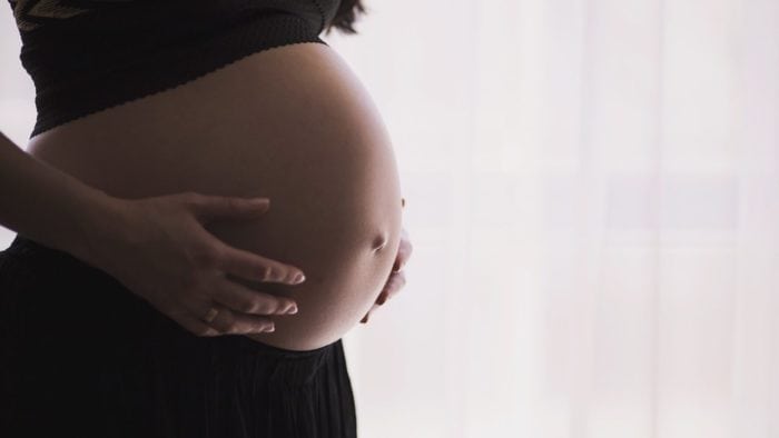 A pregnant woman holding her belly.