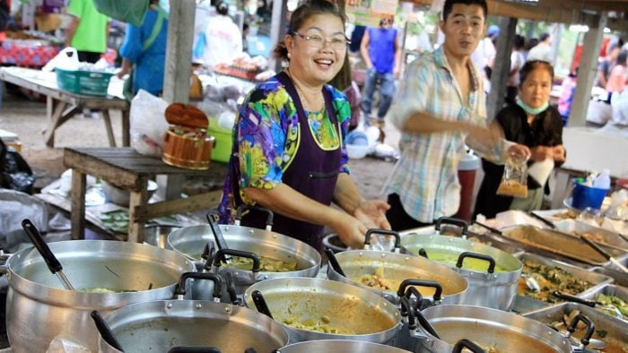 A Thai lady serving food at a street food stand in Thailand.