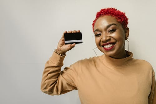 A smiling woman holding up her new credit card