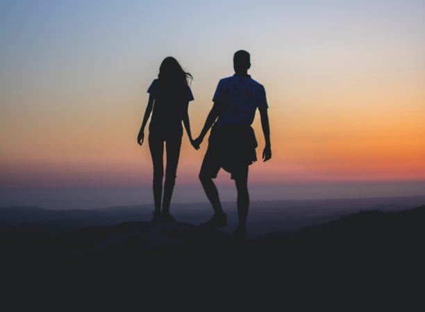 A couple holding hands at sunset