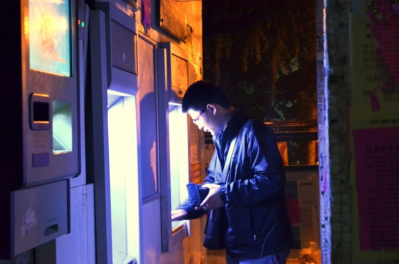 A man using an ATM machine at night