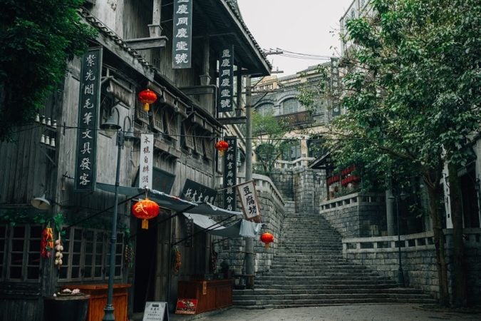 An old cobblestone street in China with trees and lanterns