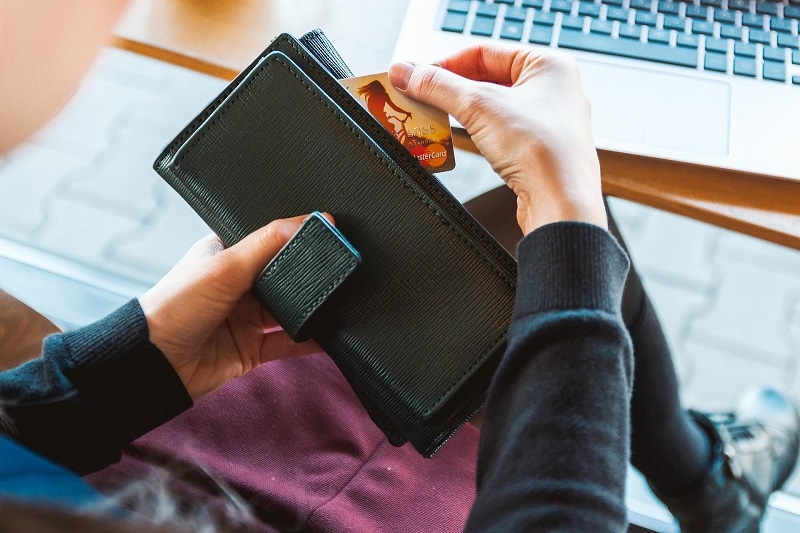 Someone removing a bank card from a black wallet