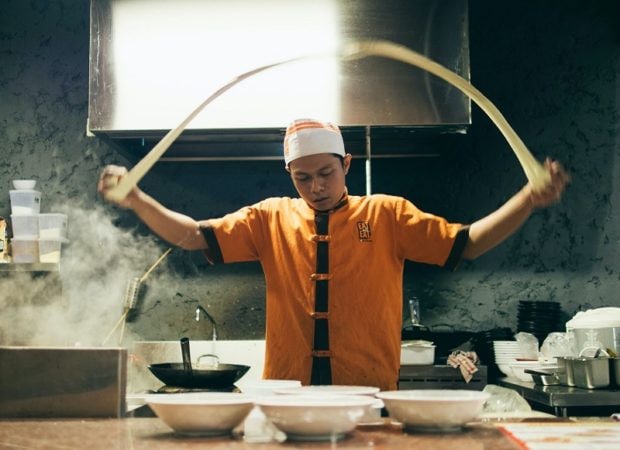 A Chinese chef making fresh pulled noodles