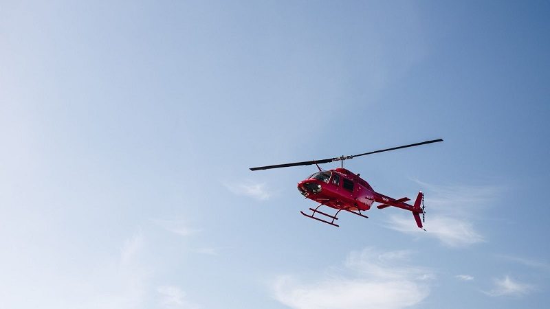 A red helicopter flying in a blue sky