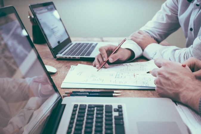 Two men with laptops doing paperwork