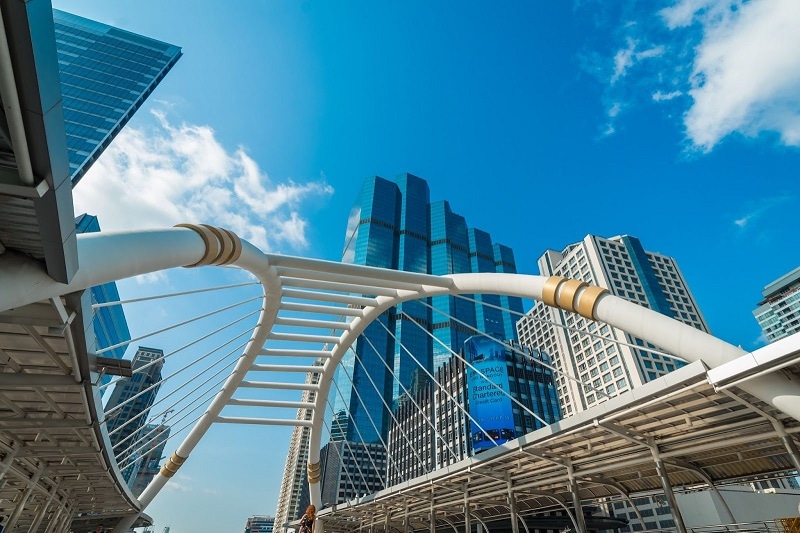 Photo of Bangkok's blue skies, tall buildings, and pedestrian bridge.