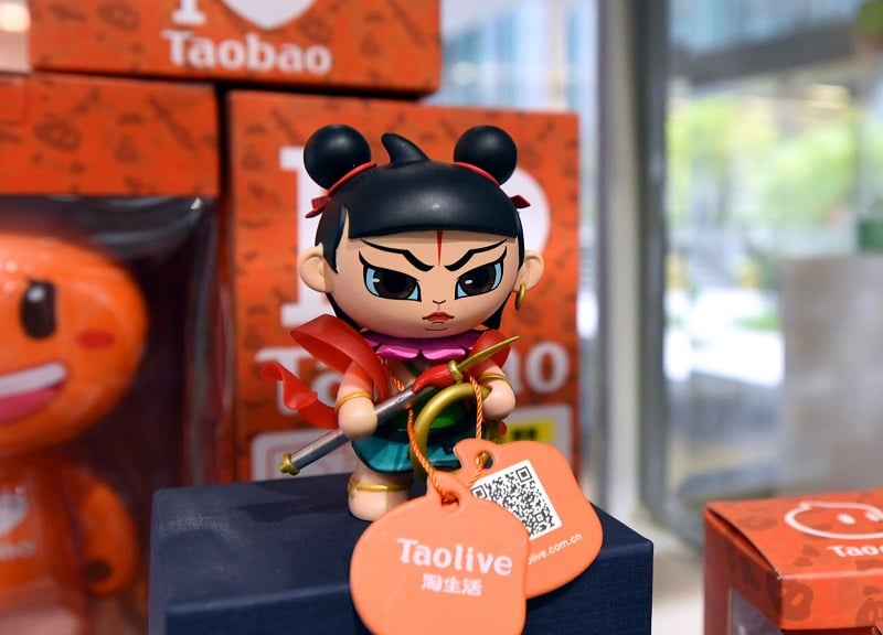 A Taobao promotional figurine with a QR code for Taolive 