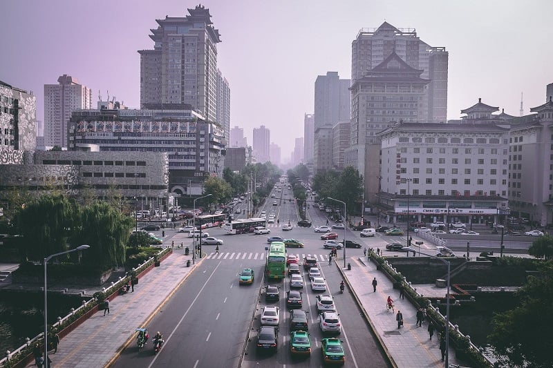 A view from above of Beijing city streets lined with buiirlings nad full of cars. 