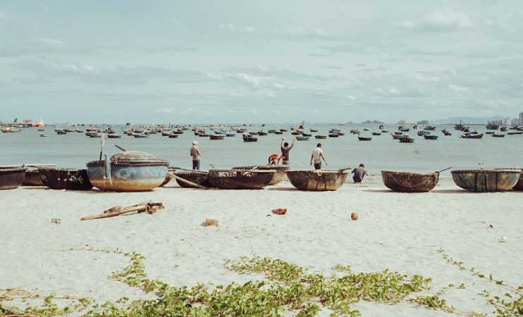 Da Nang, Vietnam. View f a beach and the ocean covered in small circular wooden boats.