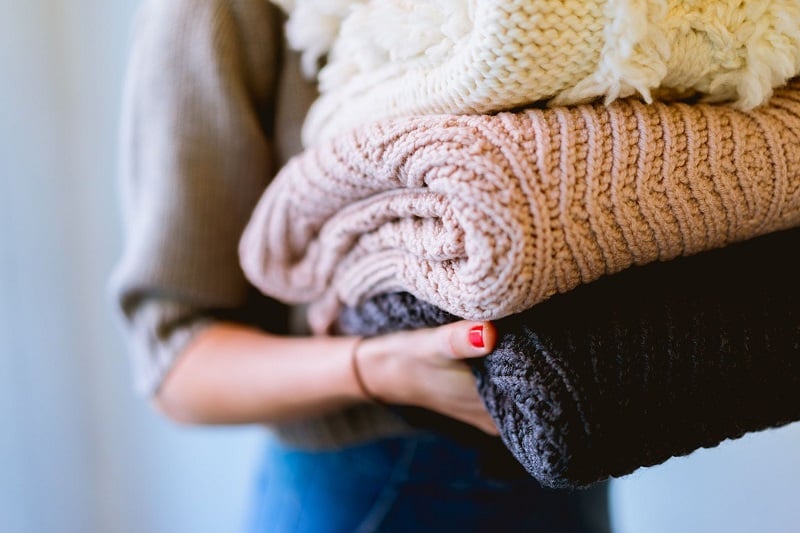 Close up of a woman's arms holding a pile of blankets. 