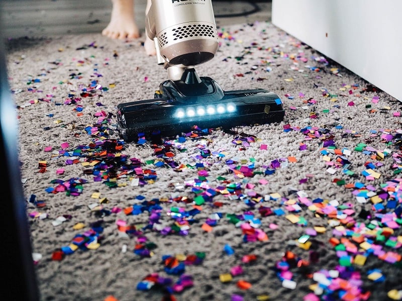 Close up photo of a vacuum cleaner sucking up confetti after a party. 