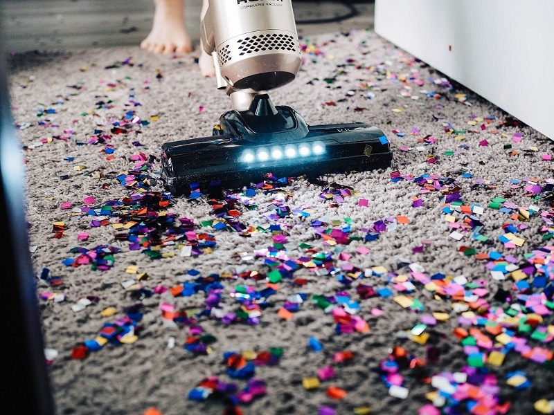Close up photo of a vacuum cleaner sucking up confetti after a party.