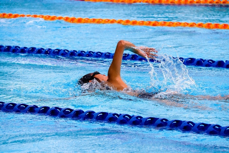 Olympic sized swimming pool at a Singapore school with a student doing laps. 