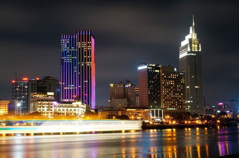 A photo of the riverside at night in Ho Chi Minh City with boats rushing by. 