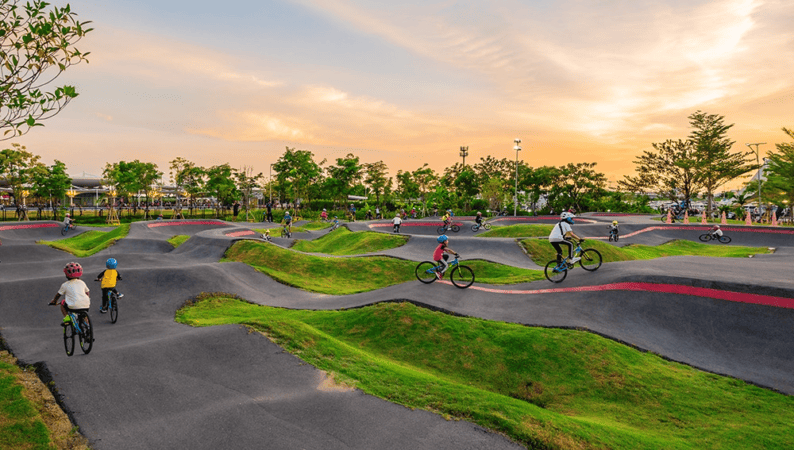 The kids area of HHBL near BKK Airport with children biking over small hills.