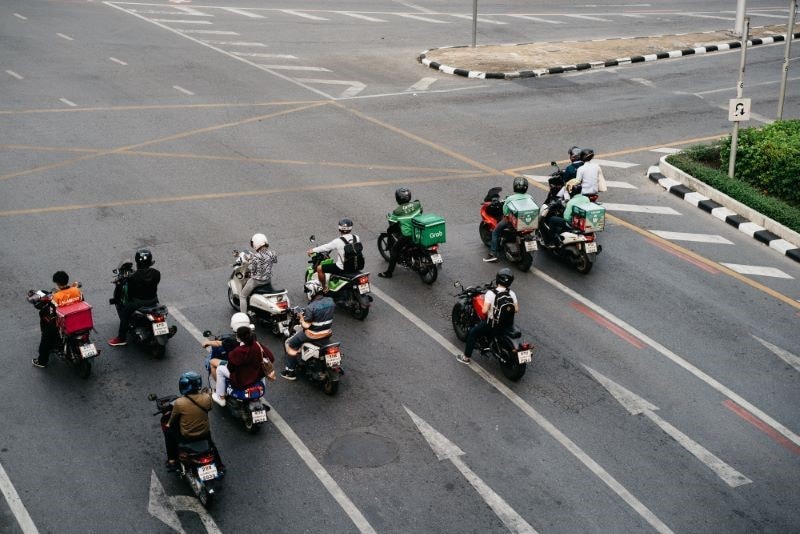 A Thai road with a dozen motorcycles waiting at a red light.