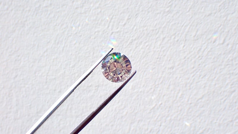 A photo of tweezers holding a diamond. 