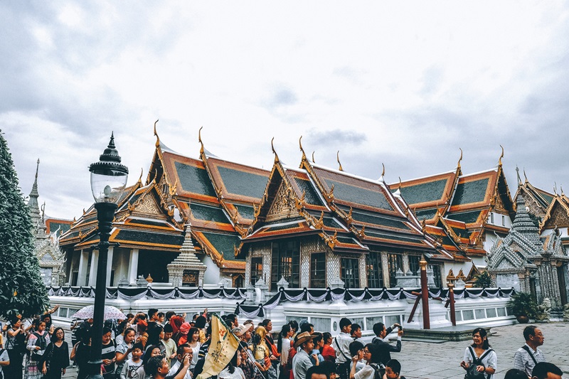 The Grand Palace in Bangkok with a tour group in front of a temple. 