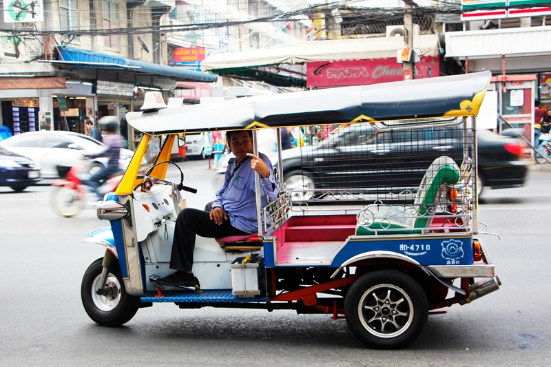 Brightly coloured tuk tuk with driver on the Bangkok streets