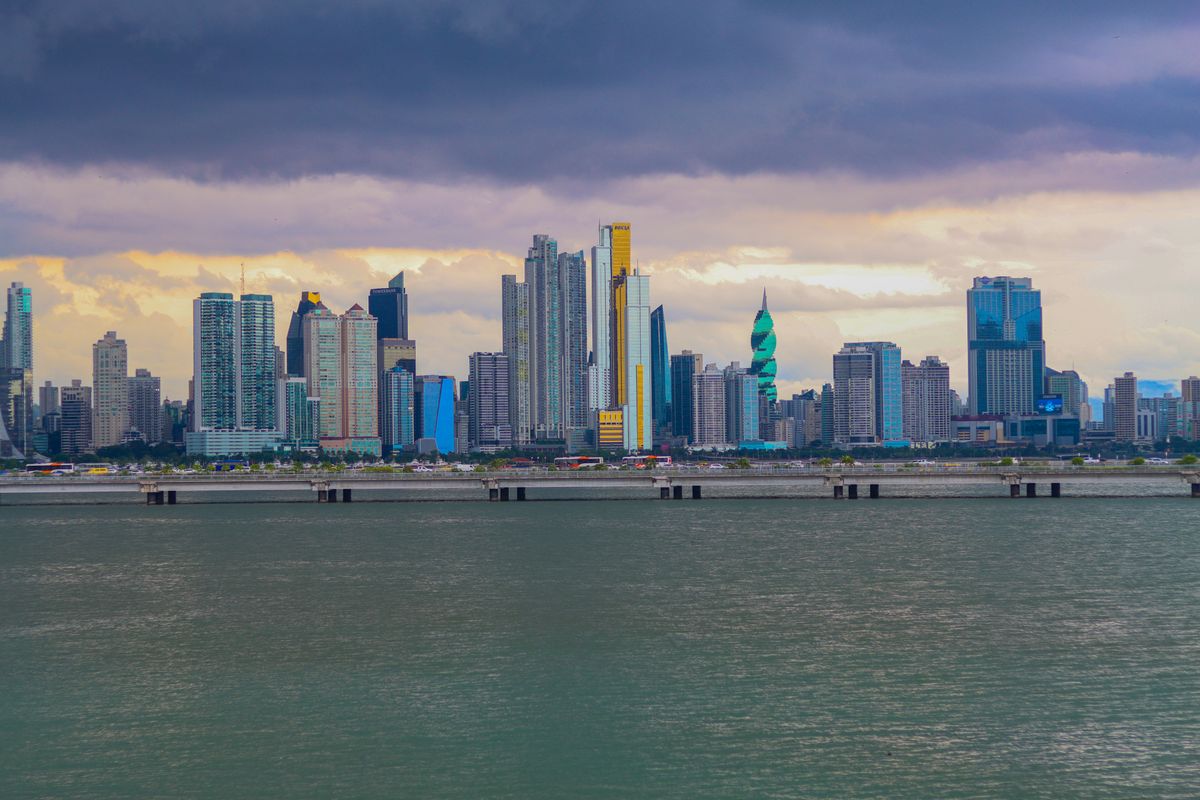 Panama City skyline viewed from the bay at dusk, with modern skyscrapers against a dramatic cloudy sky