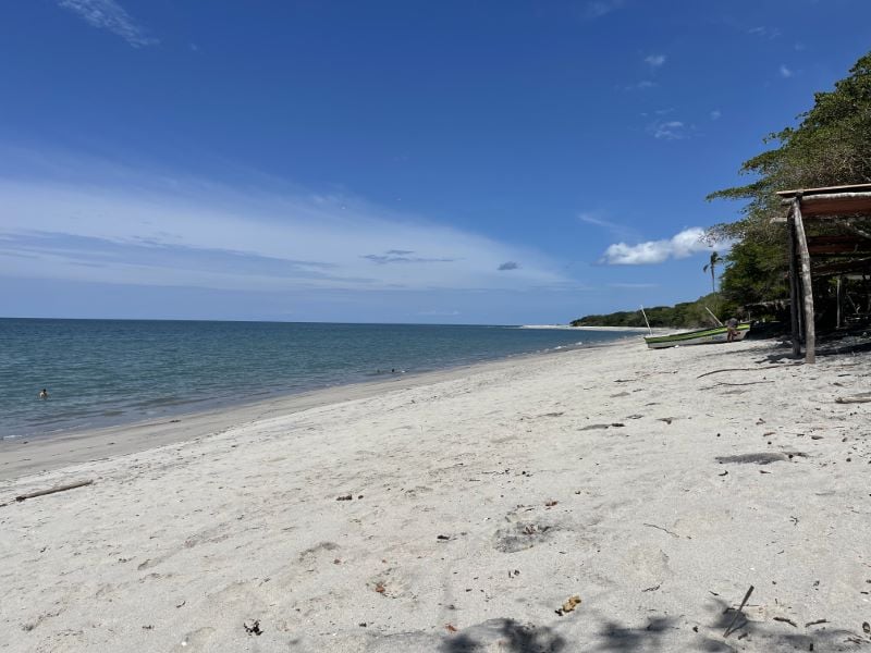 Remote white-sand beach with a fishing boat on Panama's coast
