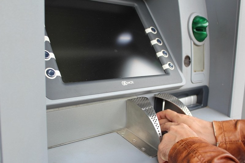 Hands entering a PIN on an ATM keypad