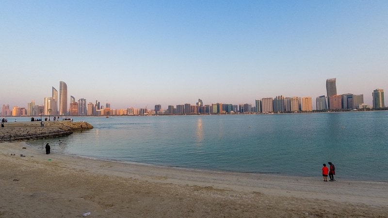 Abu Dhabi skyline seen across the water from a beach