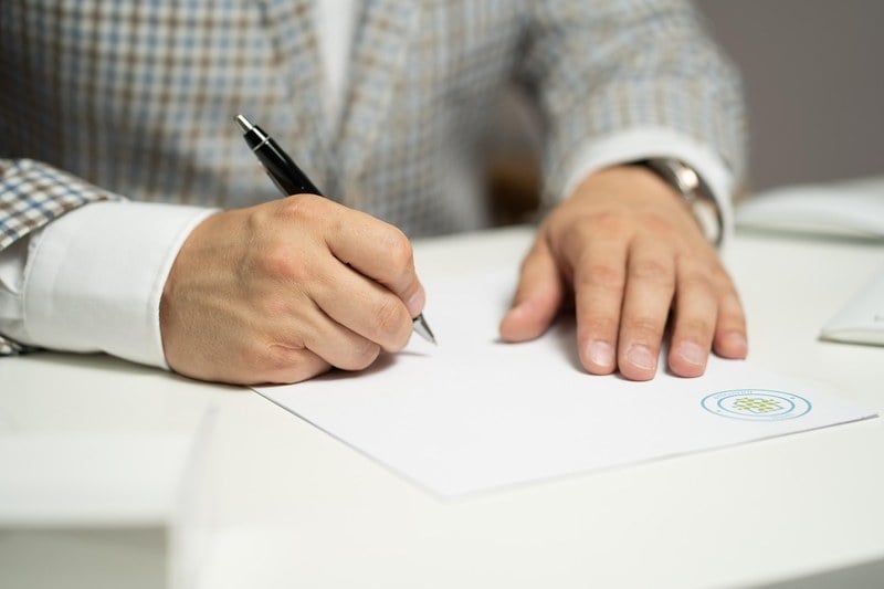Person signing a letter at a desk