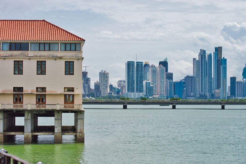 Waterfront building on pillars with the Panama City skyline across the bay